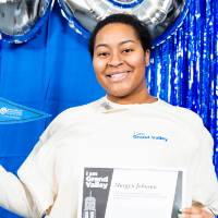student poses with certificate and GVSU flag